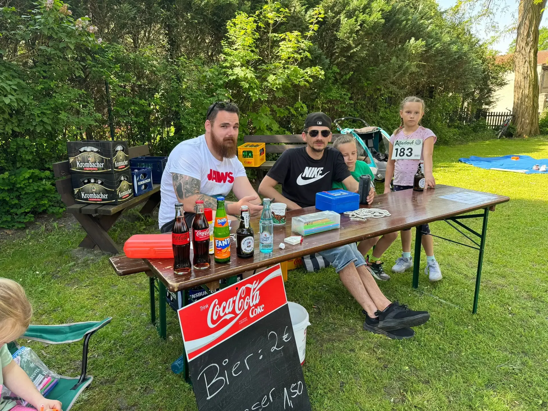 Getränkestand auf einer Wiese mit Biertisch, Getränkekisten und Helfern